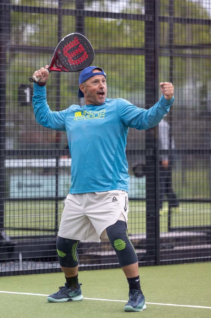 Padel player celebrating a point with arms raised at Glassbox Padel Club